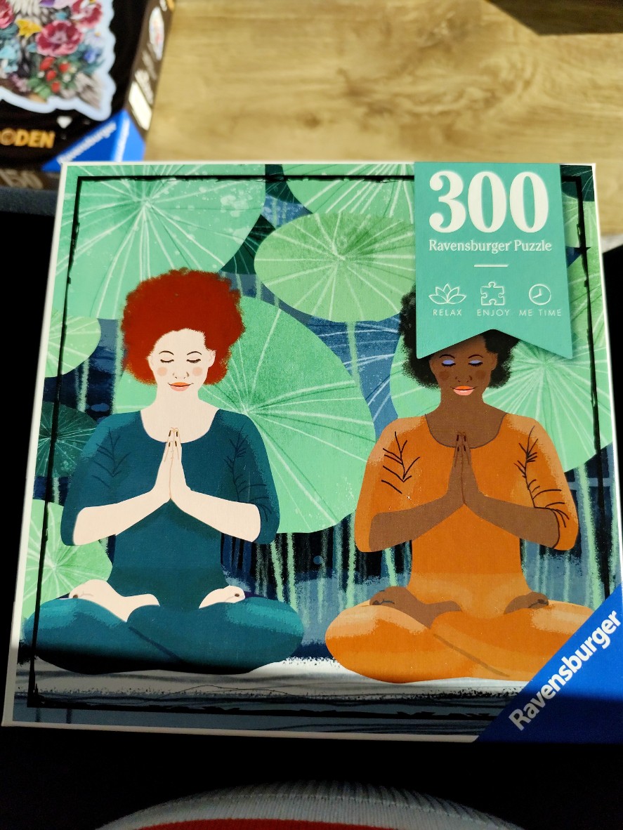 Two women with afro-style hair meditating in a lotus position against a background of large green lotus leaves.