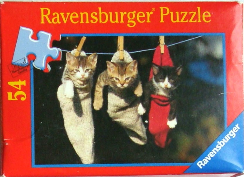 Three kittens tucked into socks hanging from a clothesline