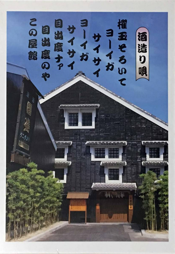 Traditional black-walled Japanese building with bamboo and Japanese calligraphy text against a clear blue sky.