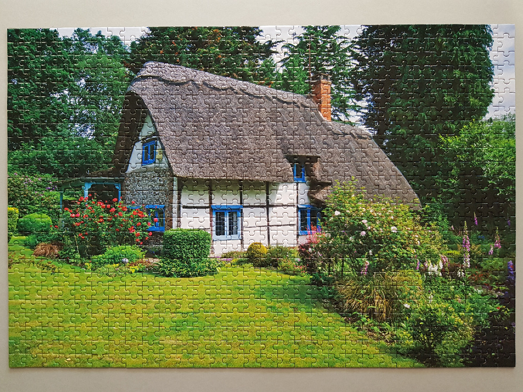 A charming English cottage with a thatched roof surrounded by a lush green garden.