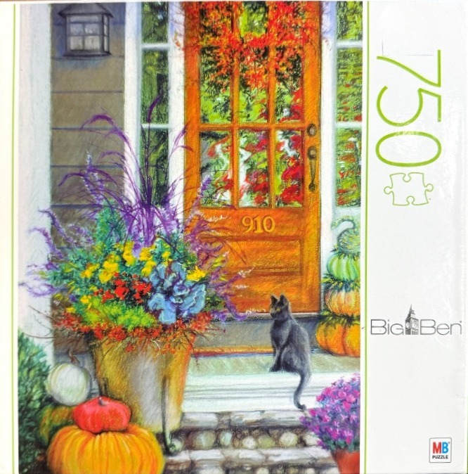 A fall scene showing a black cat sitting on a porch stoop in front of a wooden door with pumpkins and flowers.