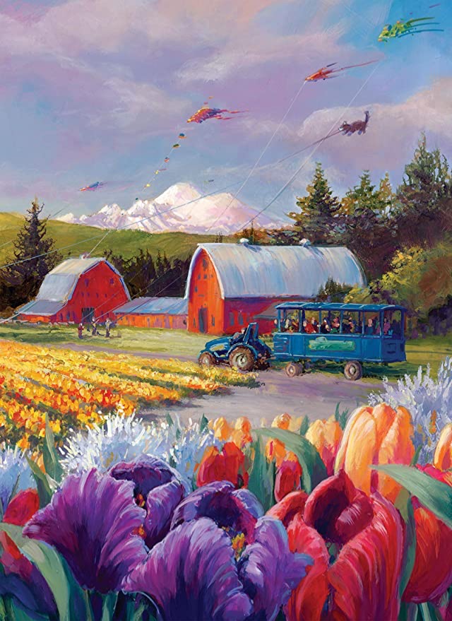 A tractor pulls a tram through a vibrant tulip field under a sky filled with kites and a distant snow-capped mountain.