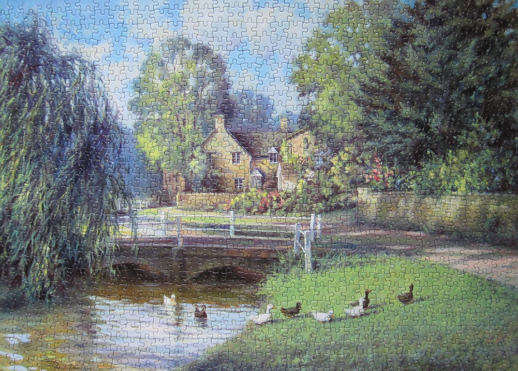 A peaceful English cottage scene with a stone bridge over a stream and a small group of ducks.