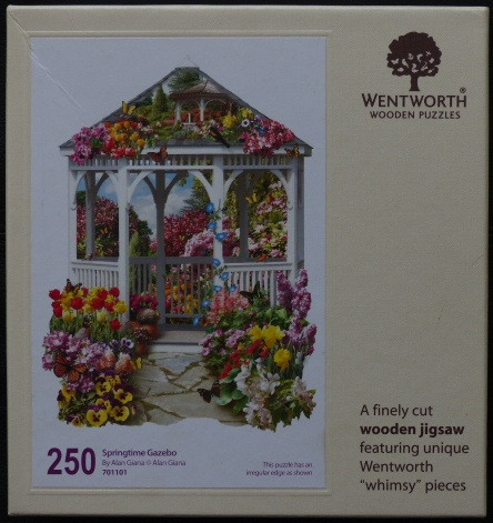 A white wooden gazebo surrounded by vibrant spring flowers and butterflies.