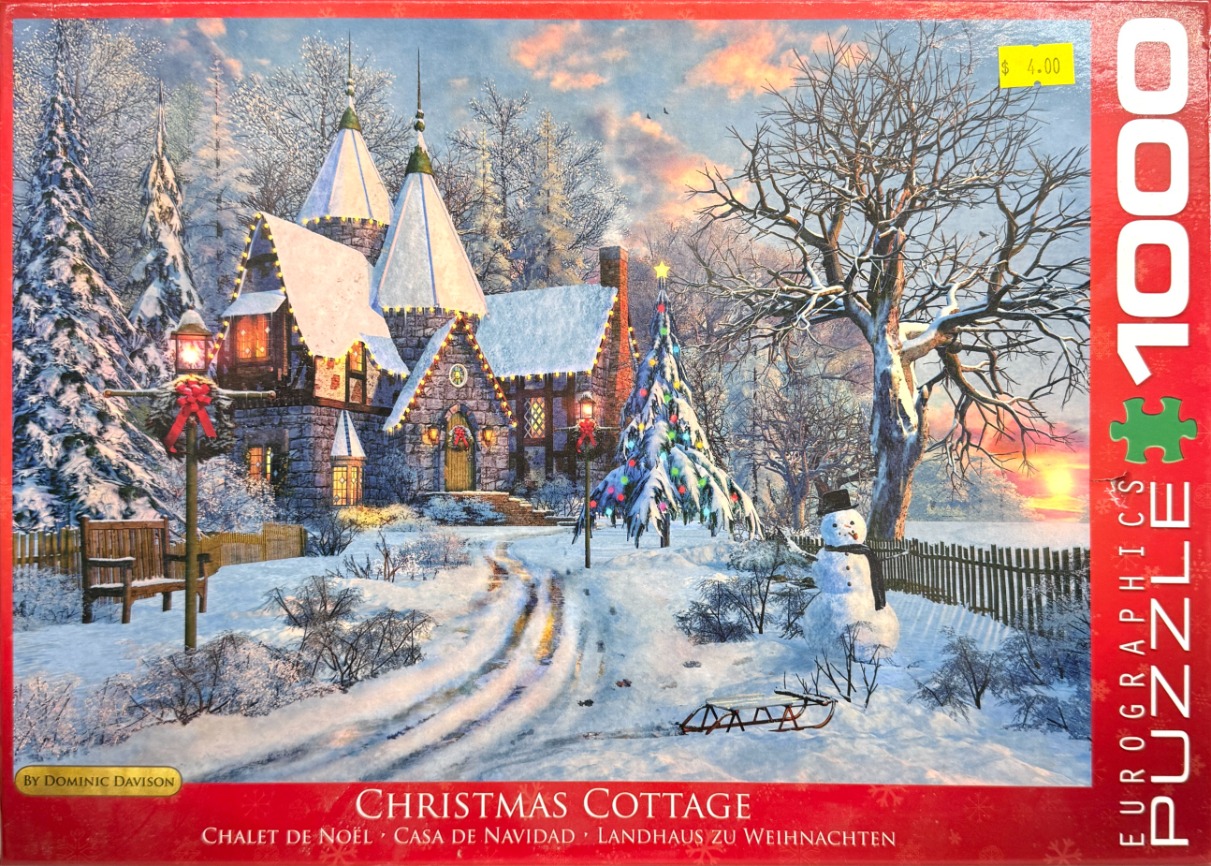 A snow-covered European-style stone cottage decorated for Christmas at sunset.