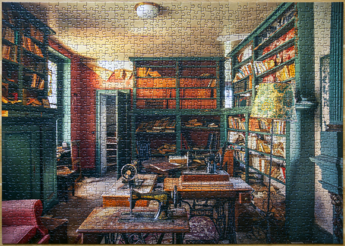 A cozy, vintage sewing room filled with antique sewing machines and floor-to-ceiling wooden bookshelves.