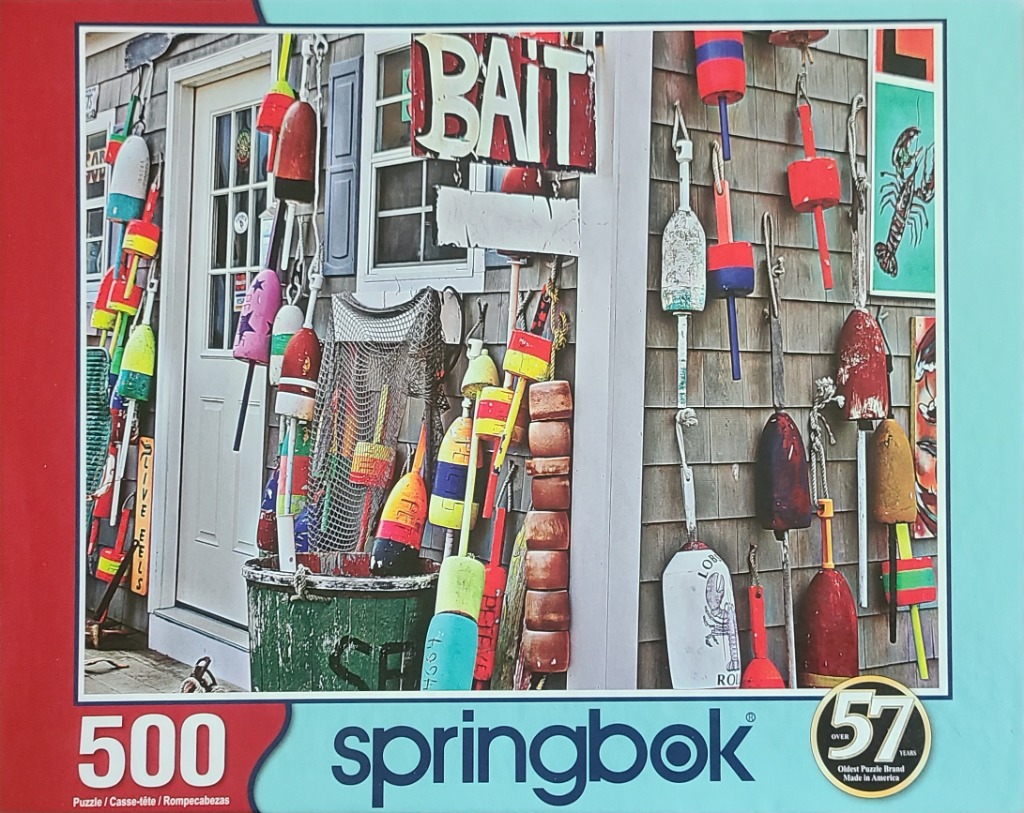 A collection of brightly colored fishing buoys and traps hanging on the side of a grey shingled building.