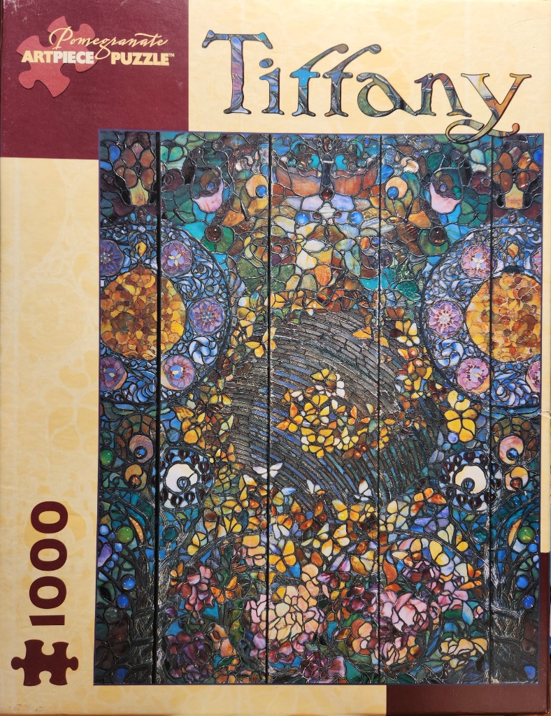 A stained glass window featuring a lush floral scene with butterflies in vibrant blues, purples, and ambers.