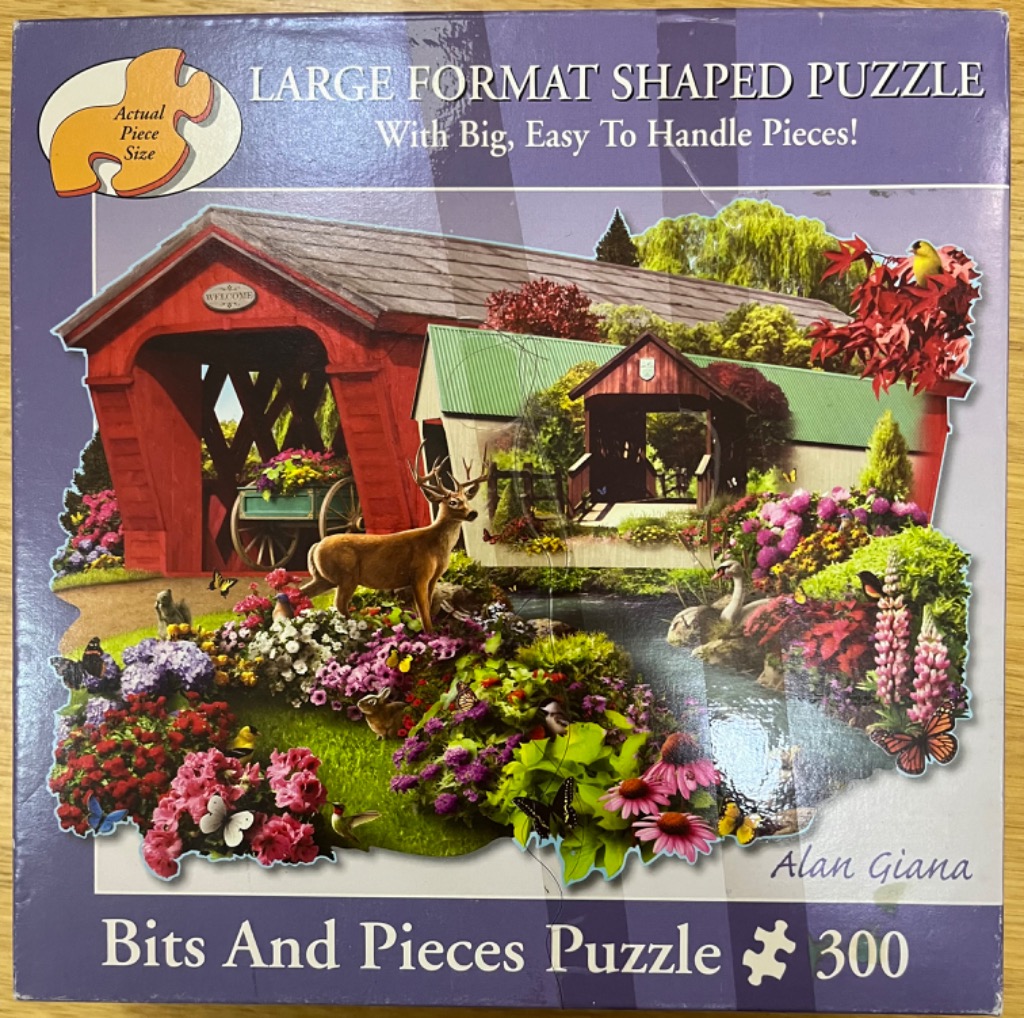 A nostalgic landscape illustration featuring a red covered bridge, a buck, and vibrant gardens.