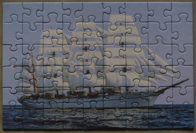 A tall ship with white sails under full canvas sailing on the open ocean.