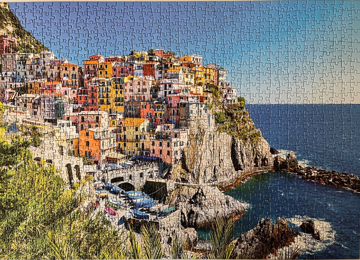 A scenic view of the village of Manarola in the Cinque Terre, Italy, built into a dramatic rocky cliffside by the sea.