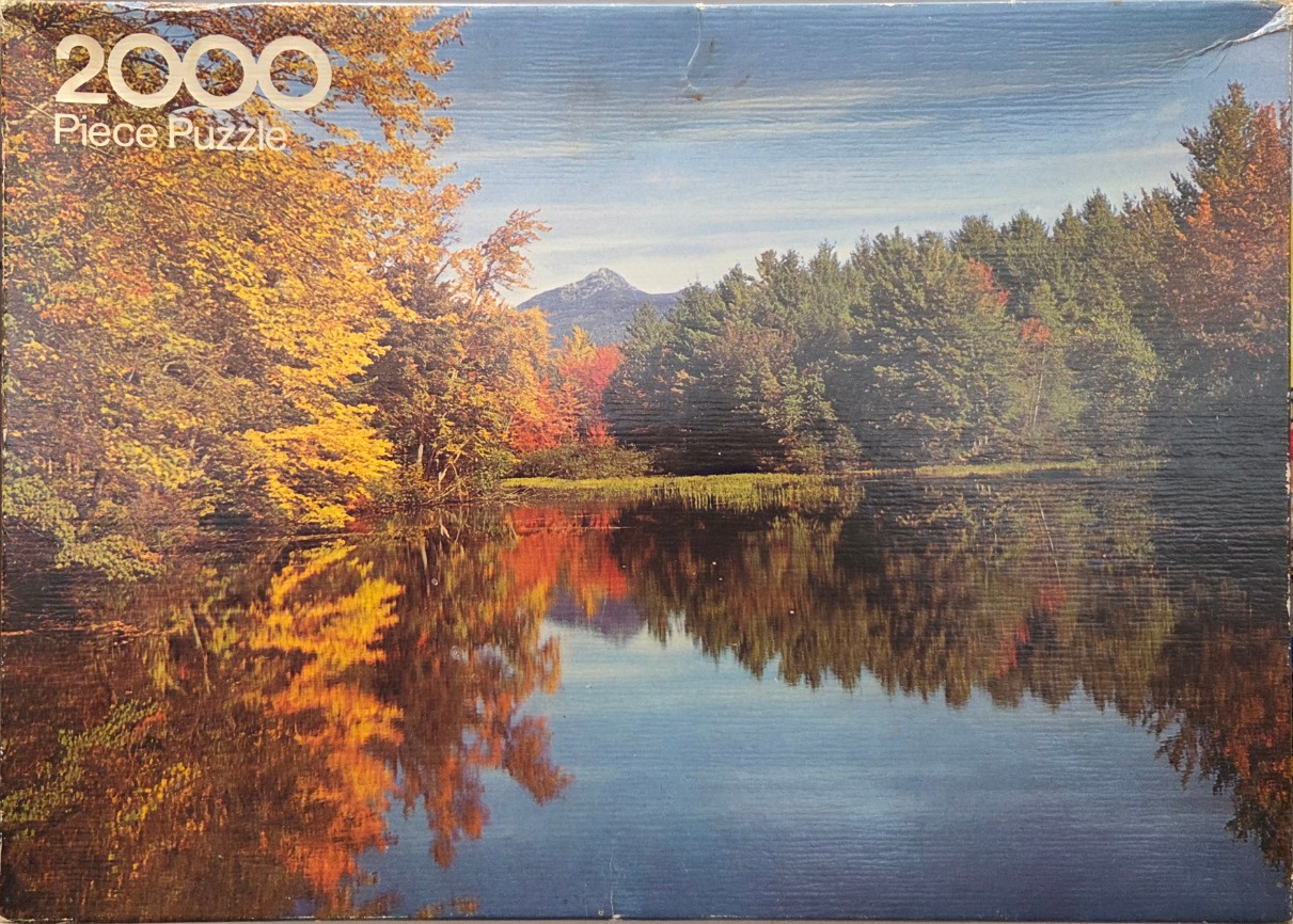 A serene autumn landscape featuring a mountain reflected in a calm lake surrounded by vibrant fall foliage.
