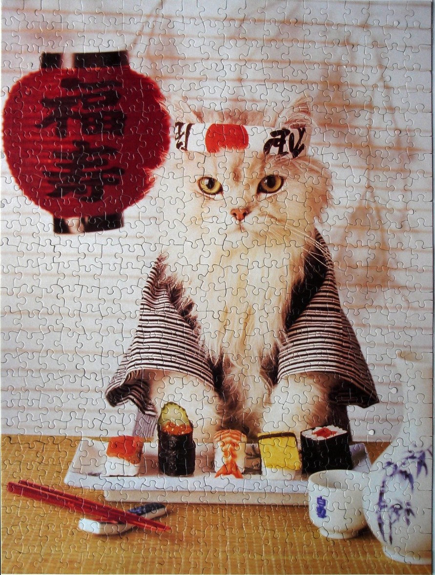 A fluffy cat dressed in a striped kimono and a red-and-white headband sits before a plate of sushi.