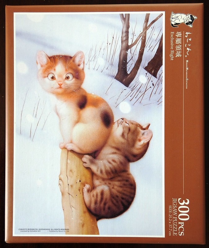 Two kittens climbing on a wooden post in a snowy landscape.