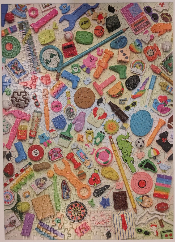 A colorful collection of various novelty shaped erasers scattered across a white grid background.