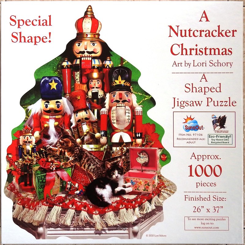 A collection of decorative nutcracker figurines and two small kittens displayed on a holiday-themed table.
