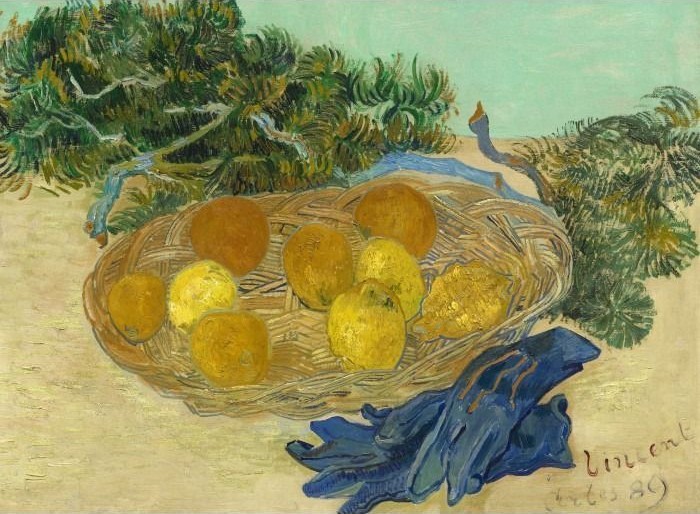 Still life of a wicker basket filled with yellow lemons and oranges, with blue gloves in the foreground.