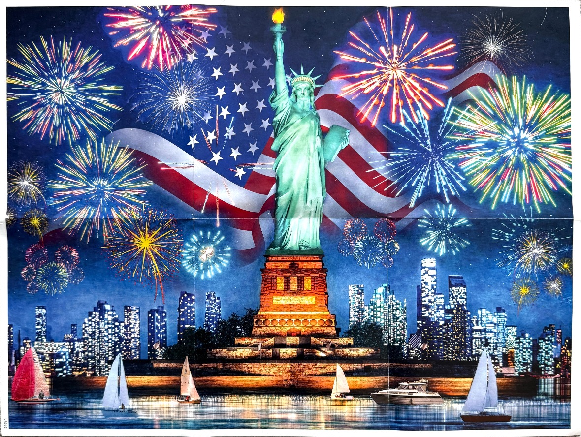 The Statue of Liberty stands center under a night sky filled with fireworks and a large American flag.