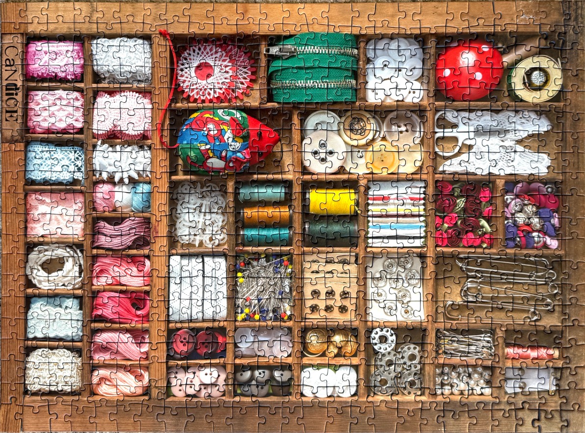 A wooden printer's tray filled with organized sewing notions and haberdashery supplies