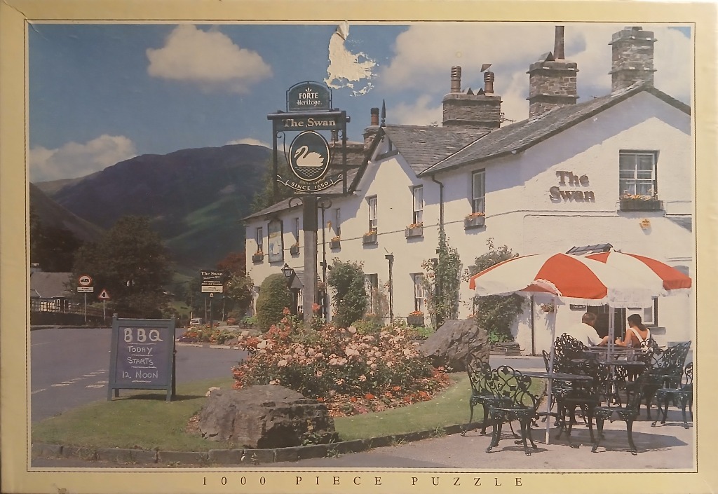 A sunny day at The Swan pub in the Lake District, featuring outdoor seating and mountain views.
