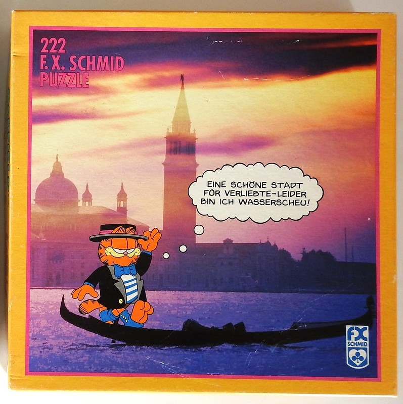 Garfield the cat wearing a tuxedo and hat in a gondola against a Venetian sunset, with a speech bubble in German.