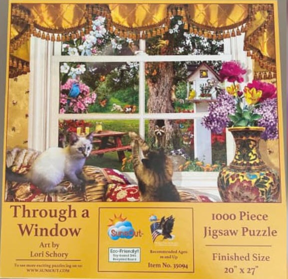Two cats looking out a window at a garden with a birdhouse, lilac flowers, and a picnic table.