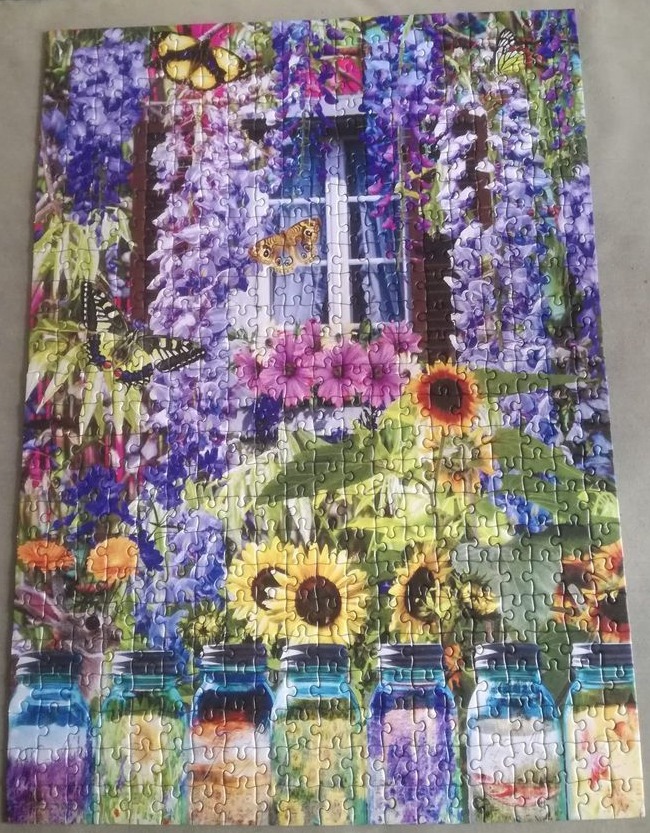 A window framed by blooming purple wisteria and butterflies, with sunflowers and glass jars in the foreground.