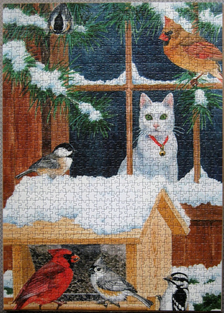 A white cat watches winter birds through a snow-covered window frame.