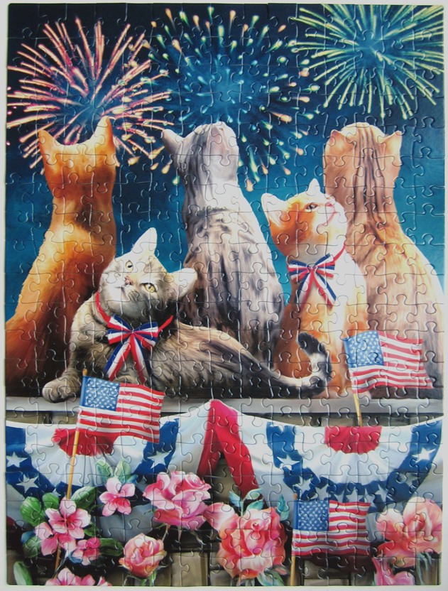 Five cats of various colors watching a Fourth of July fireworks display above patriotic bunting and flowers.