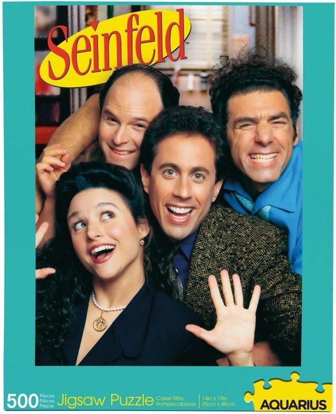 Four main characters from Seinfeld posing and smiling together for a cast portrait.