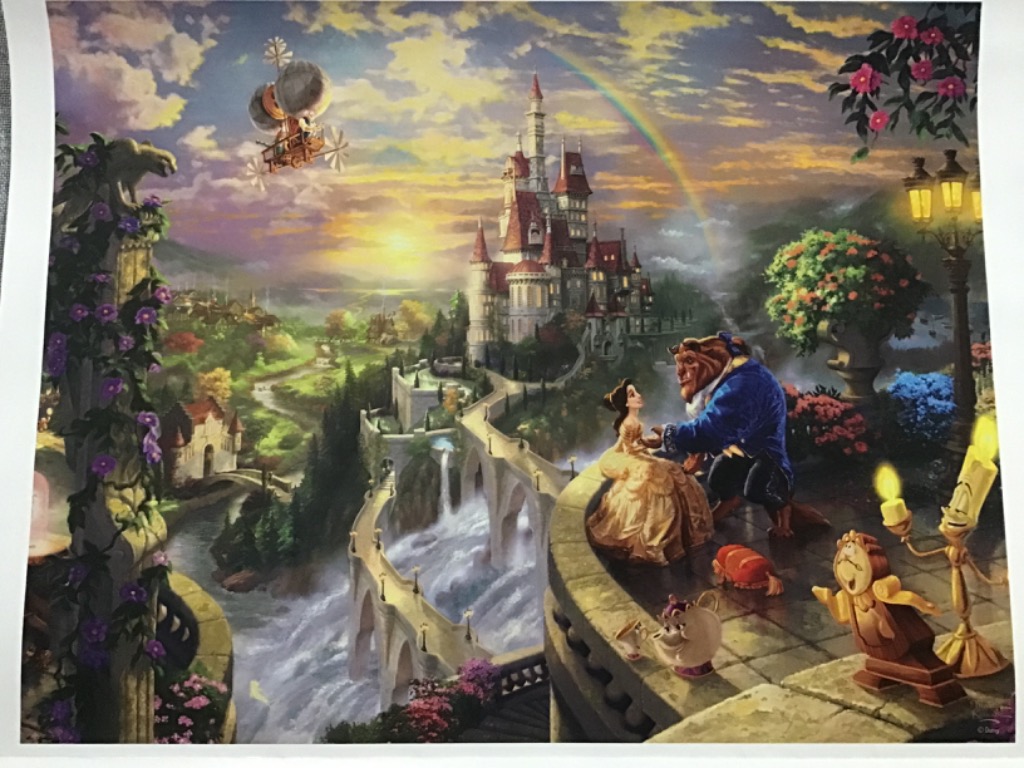 Belle and the Beast stand on a balcony overlooking a fairy tale castle with a rainbow in a sunset sky.