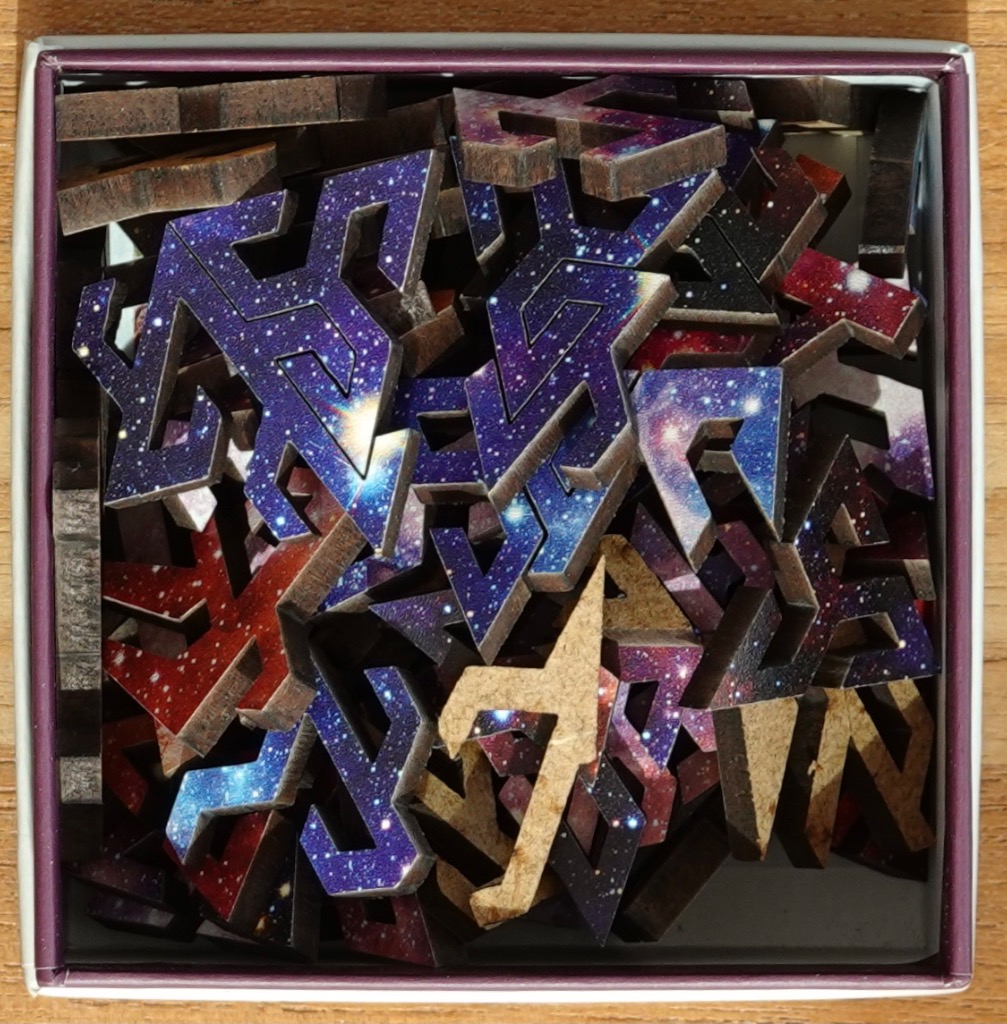 A collection of dark, geometric, galaxy-printed wooden pieces jumbled together.