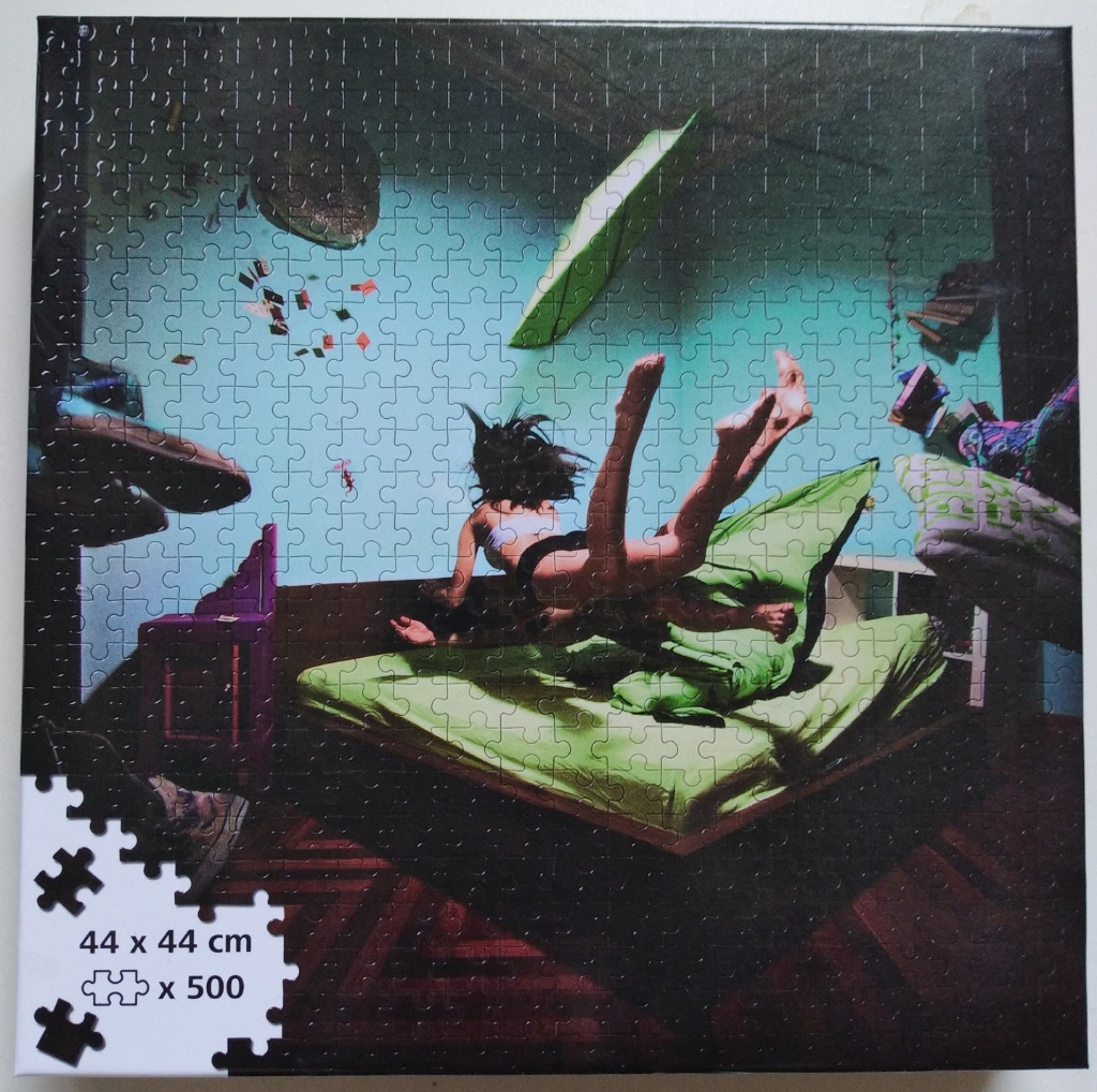 A person floating horizontally above a bed in a room with levitating objects