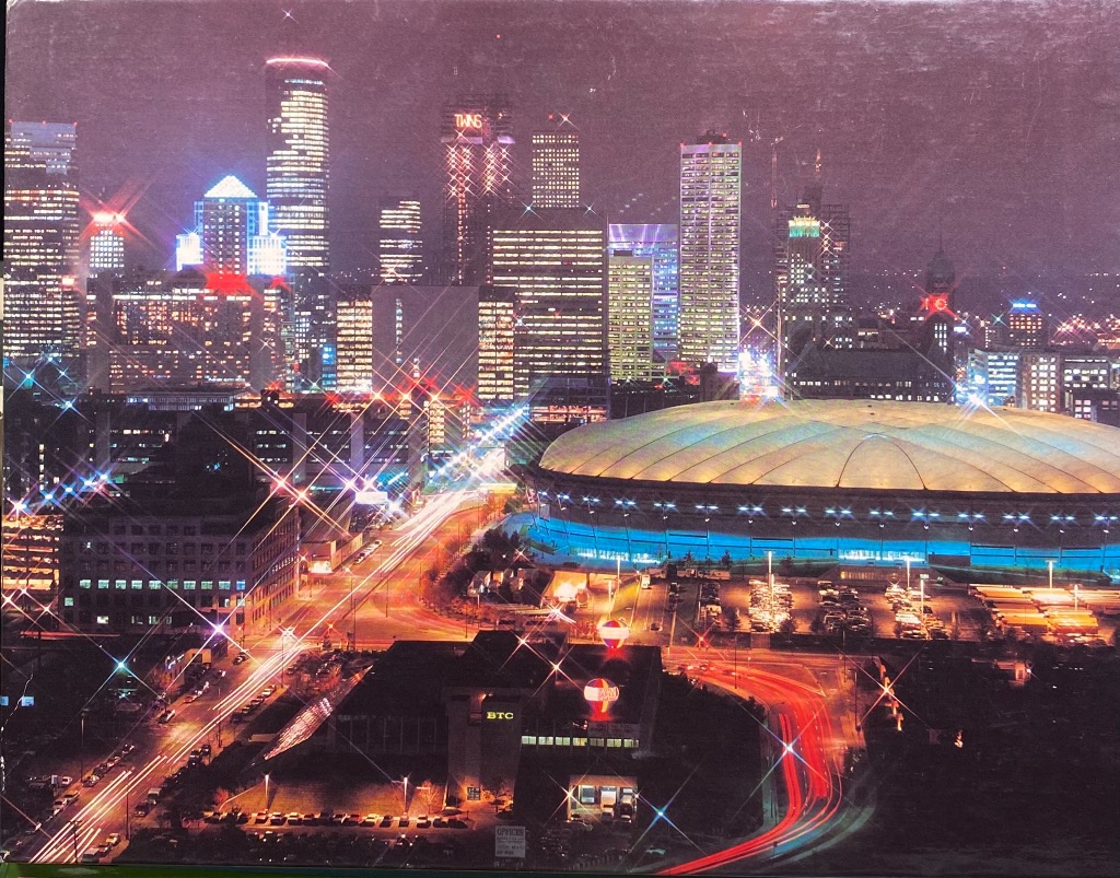 Night view of the Houston skyline featuring the Astrodome with starburst lighting effects.
