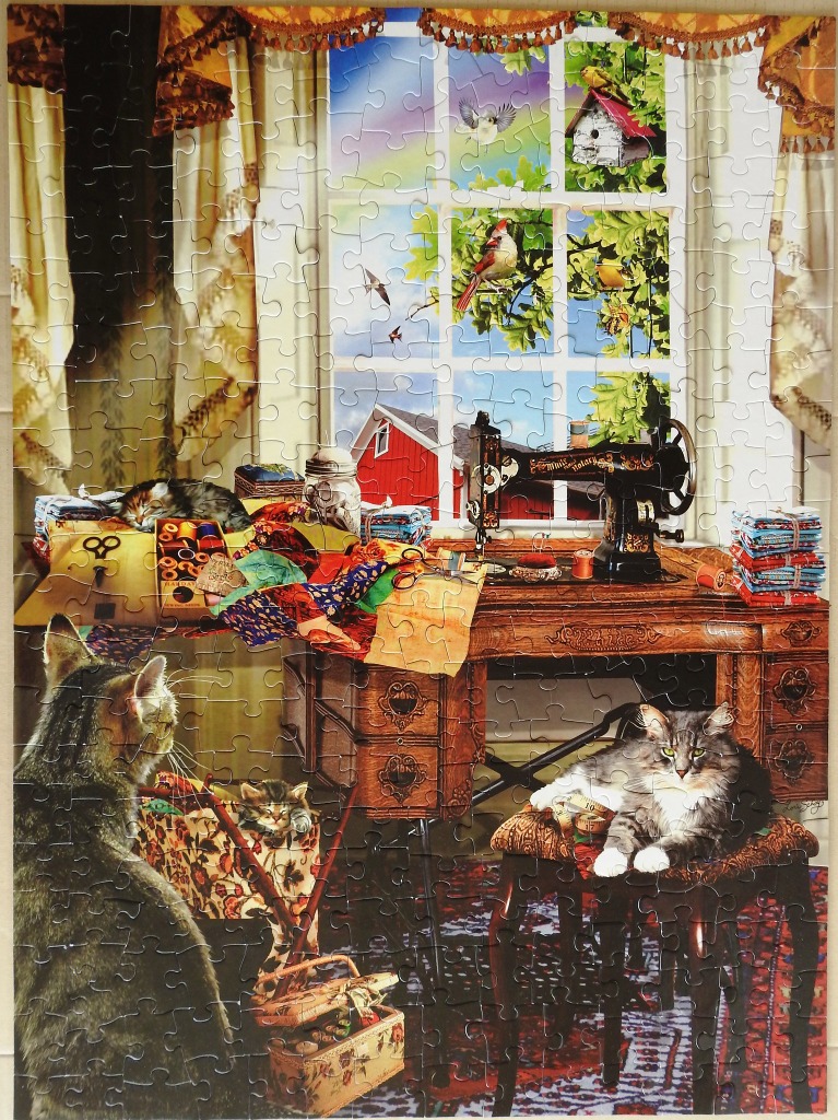 A cozy craft room scene featuring a vintage sewing machine, fabric, and three cats looking out a window.