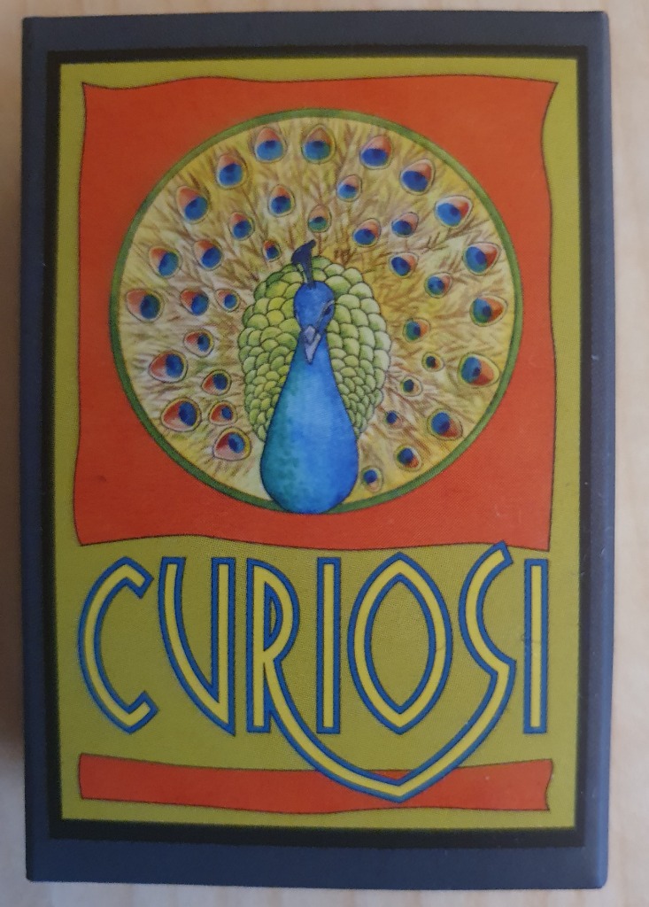An illustrated peacock with a fanned tail centered above the word CURIOSI in an art deco style.