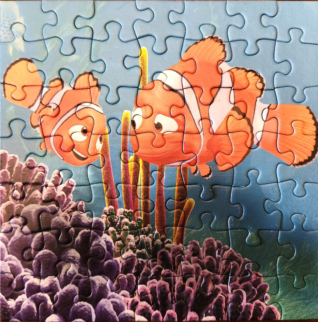 Two clownfish swimming near a coral reef underwater.