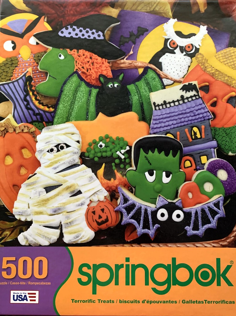 A collection of colorful Halloween-themed decorated sugar cookies featuring a mummy, witch, frankenstein, and bats.
