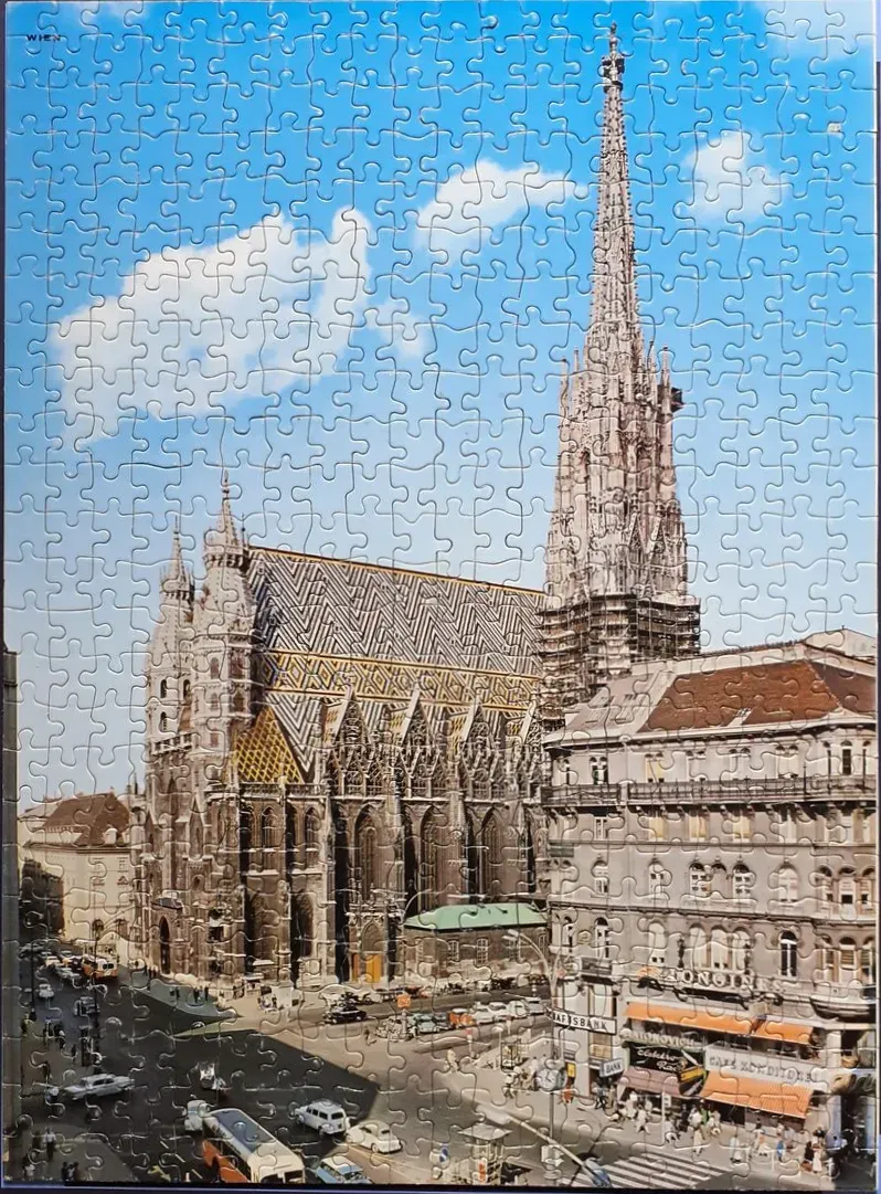 St. Stephen's Cathedral in Vienna with its iconic mosaic tile roof and tall gothic spire above a city street.