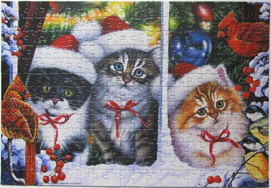 Three fluffy kittens in Santa hats surrounded by winter greenery, berries, and cardinals.