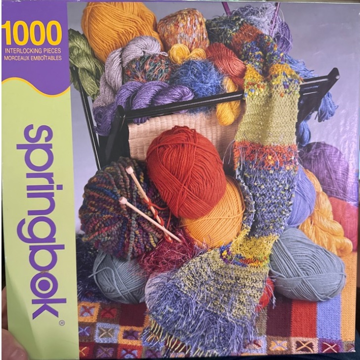 A collection of colorful yarn balls and a knitted scarf in a basket.