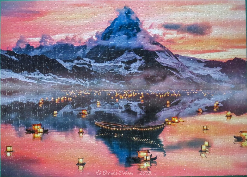 A majestic snow-capped mountain behind a lake filled with glowing lanterns and a wooden boat at sunset.