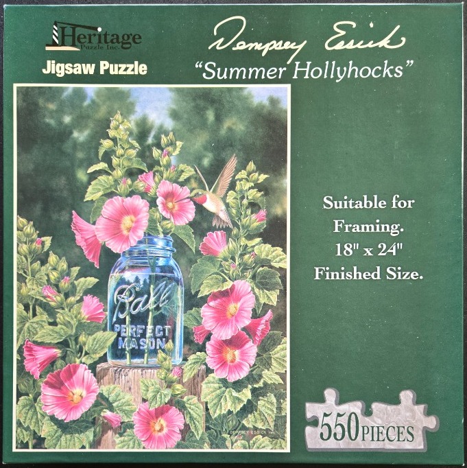A hummingbird hovers near pink hollyhocks in a glass mason jar on a wooden post.