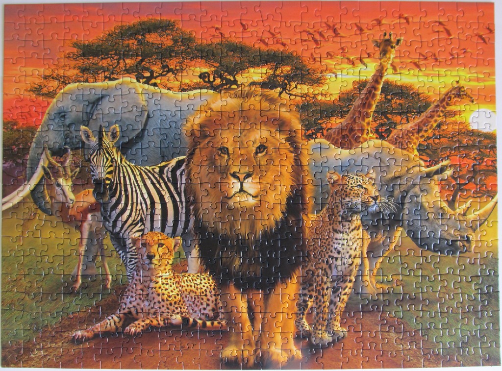 A group of African safari animals standing together against a vibrant orange sunset.