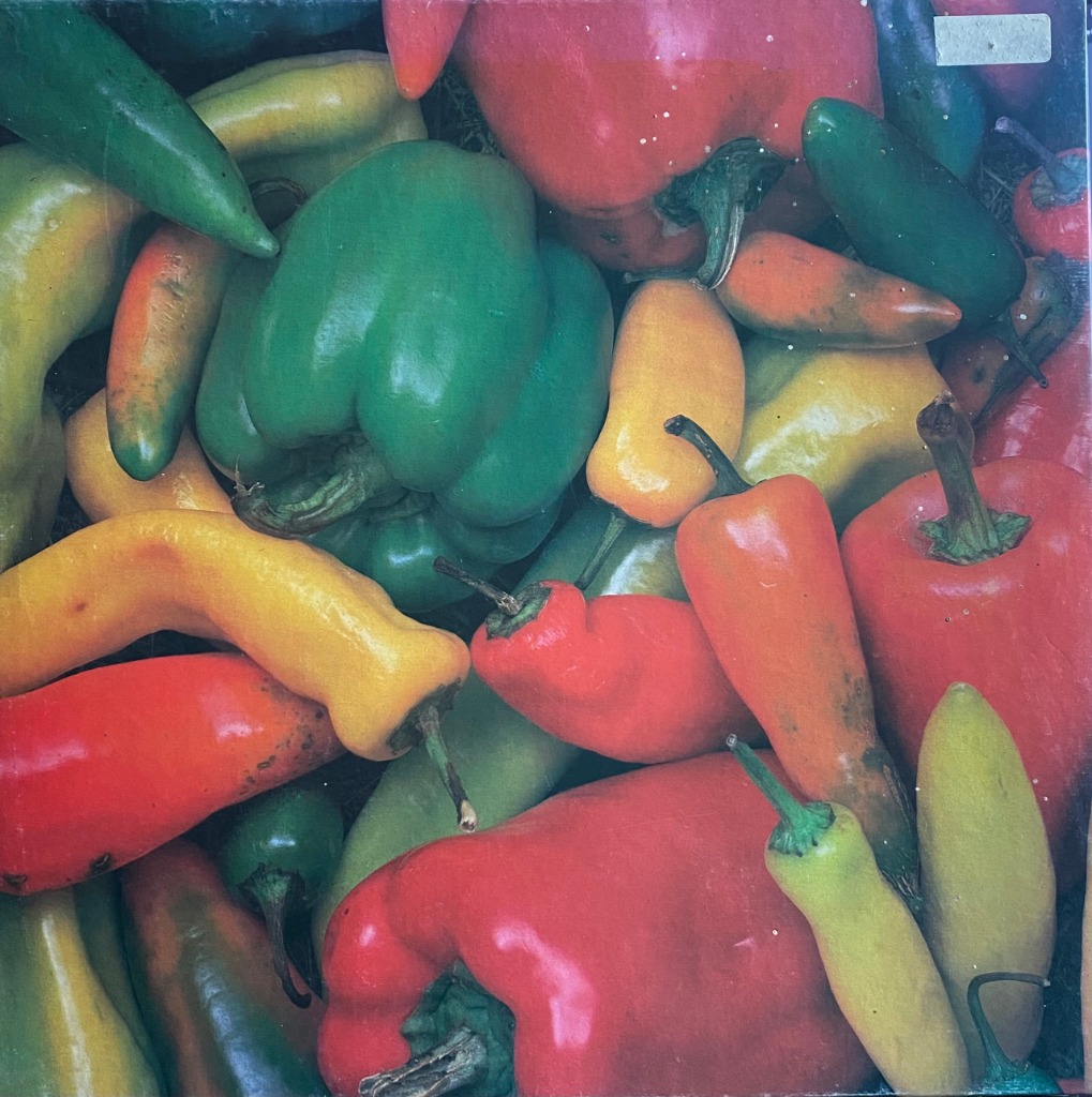 A close-up photograph of a vibrant, dense cluster of bell and chili peppers in red, green, and yellow.