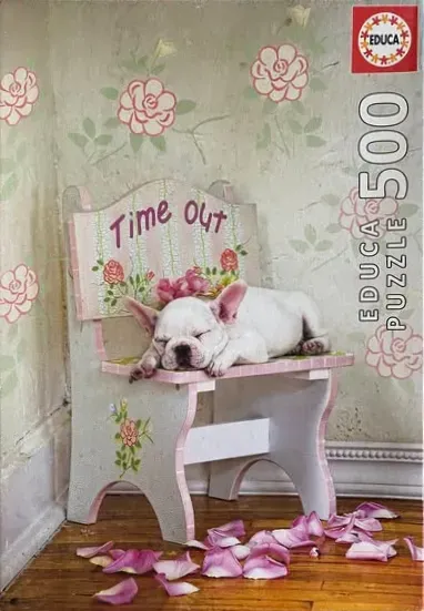 A white French bulldog puppy sleeping on a small, hand-painted wooden chair labeled Time Out.