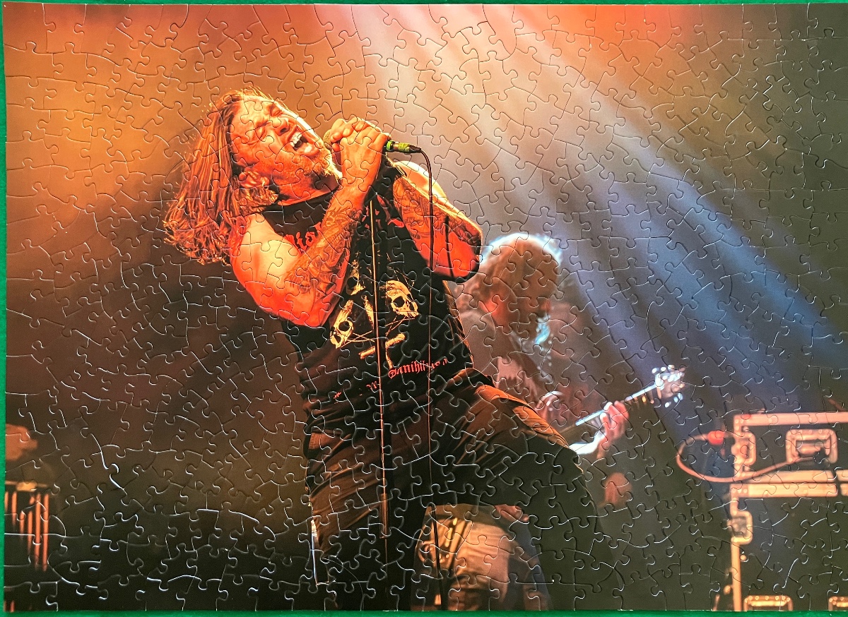 A male rock singer performing passionately into a microphone on stage under dramatic lighting.