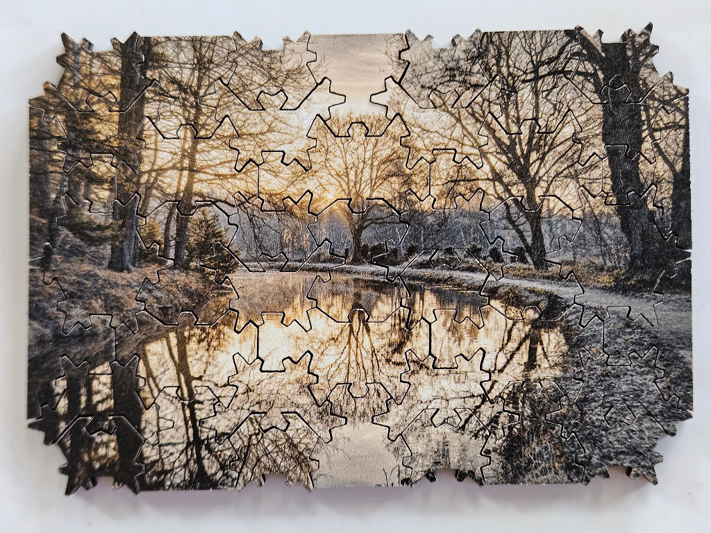 A serene photograph of a canal and bare trees at sunrise with soft golden light reflected in the water.