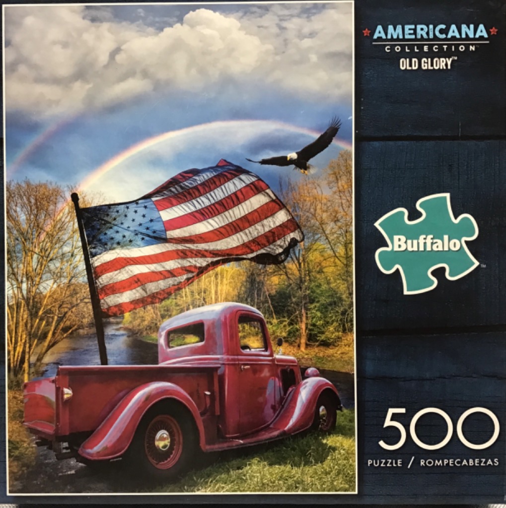 A red vintage pickup truck parked by a river with a large American flag and a bald eagle flying under a rainbow.