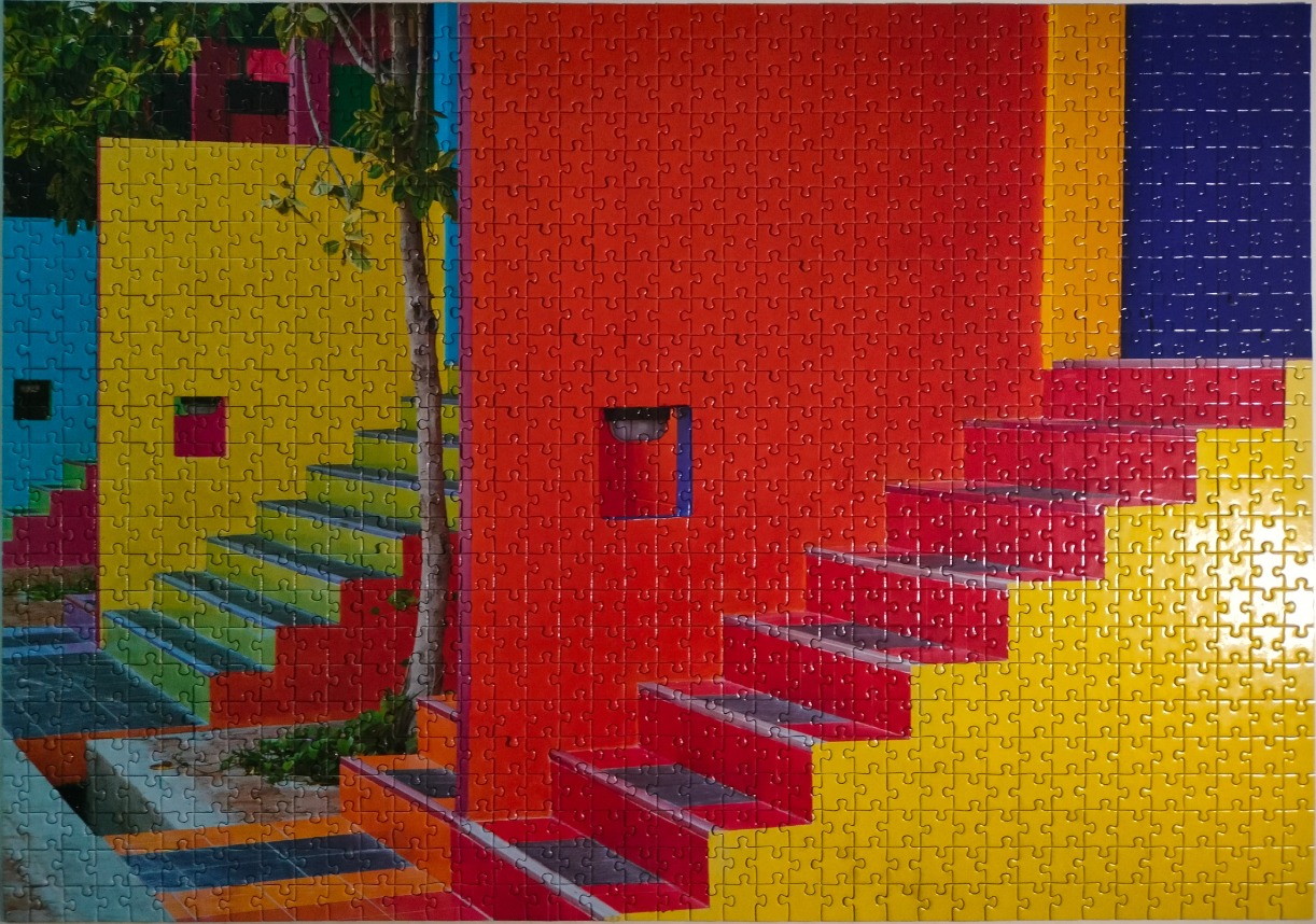 A vibrant architectural photograph of a brightly colored, geometric staircase set against solid red and yellow walls.